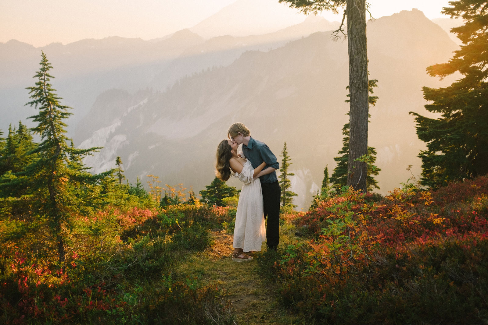 A couple stands on a mountain ridge at golden hour in the North Cascades