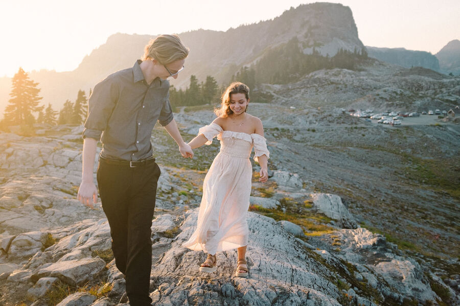 Couple walking on rocks below a Cascade peak at golden hour