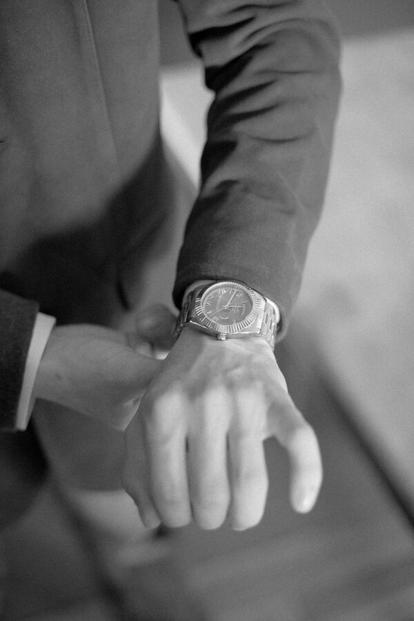 Black and white groom adjusting his watch before the ceremony